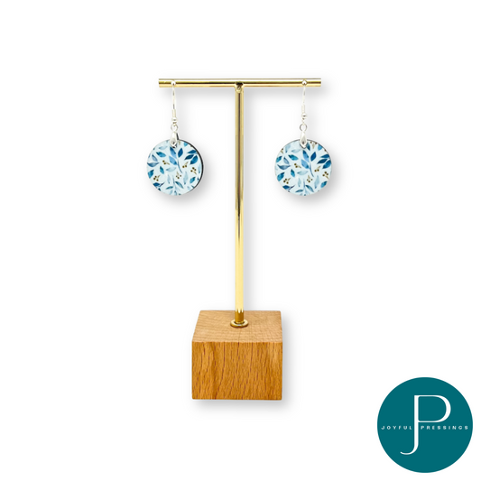 Blue leaf pattern on round shape earrings.  Displayed on a stand.