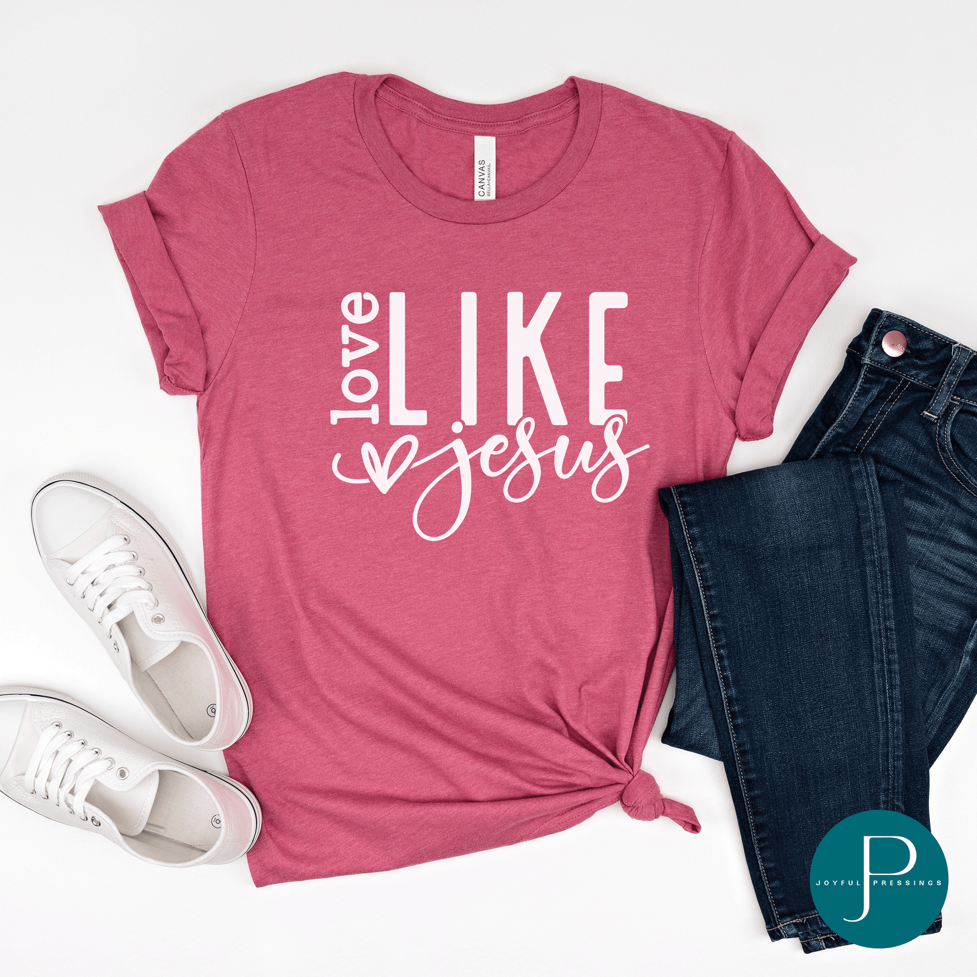 Flatlay picture of the Love Like Jesus white print on a heather raspberry tee.