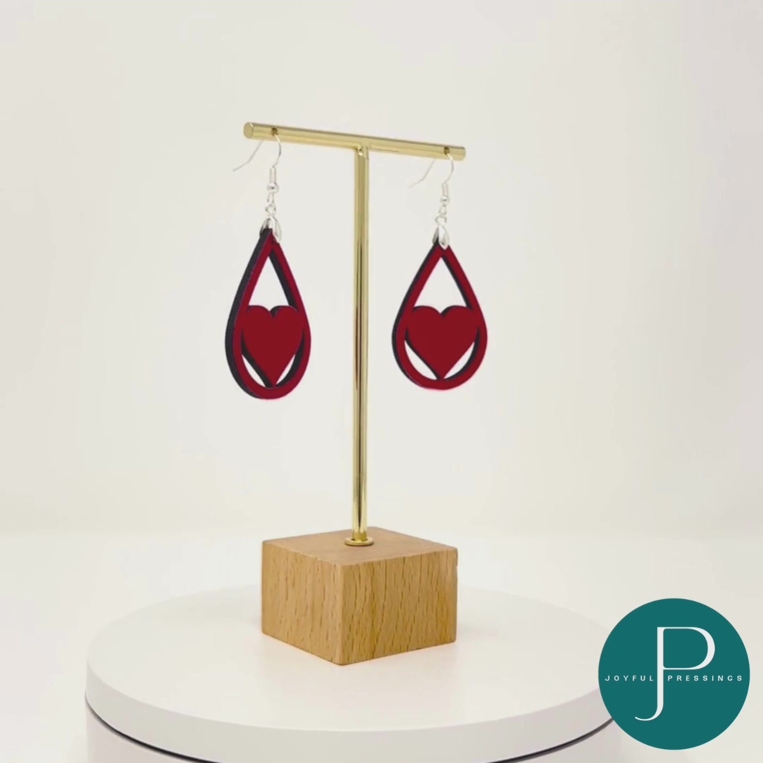 red heart teardrop earrings displayed on a stand in a rotating video