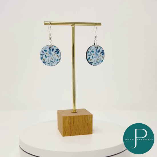 Blue leaf pattern on round shape earrings.  Displayed in a rotating video.